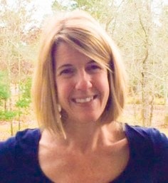 A woman with blonde hair and blue shirt smiling.